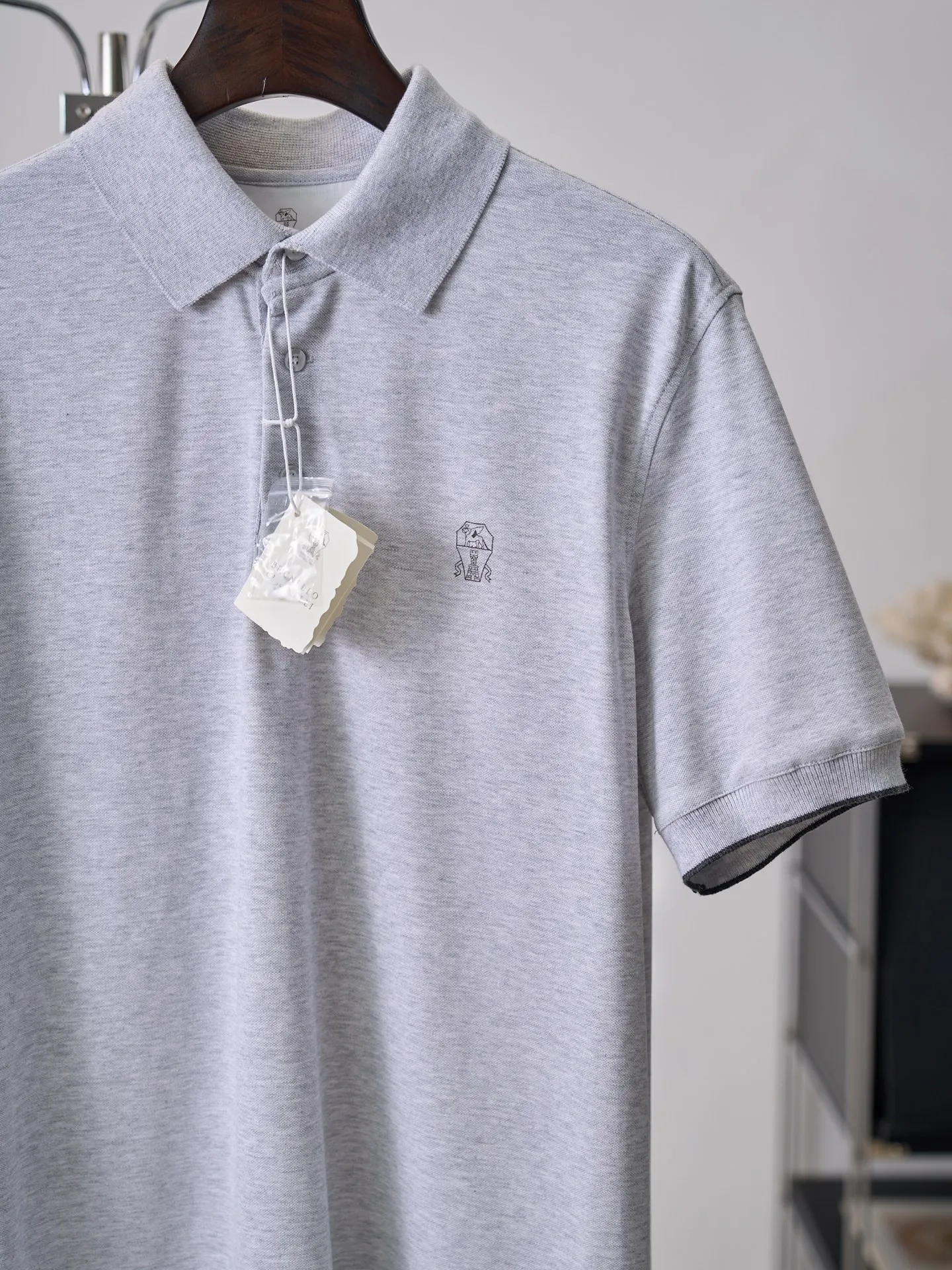 [In-Stock] Brunello Cucinelli/BC pattern print polo polo shirt [In Stock] S M L XL Fabric selection: High-count combed cotton pique fabric is used. Through the iconic honeycomb pique mesh weaving method, the fabric surface is covered with even Breathable micropores. The hollow structure accelerates air circulation and can quickly wick away sweat and moisture. It will not be stuffy or sticky when worn for a long time. At the same time, combed cotton is soft and skin-friendly, and is crisp and stylish. The upper body is not easy to collapse and wrinkle, and has a neat silhouette. Auxiliary rib fabric: The contrasting color thin edge ribs on the cuffs are made of cotton knitted with the same material. The horizontal strips have stable elasticity and the cuffs are tight without constricting the arms. The contrasting color strips enhance the sophistication of the details. Printing process: Accurately position the printing coordinates of the body, and perform high-temperature smoothing on the pique fabric and collar before printing to avoid pattern blurring and line breakage caused by uneven fabrics during screen printing. Use low-consistency matte water-based environmentally friendly glue, and apply the sizing in two thin scrapings. The first layer is used to lock the color, and the second layer is used to finely outline the pattern lines. It is dried in sections at low temperature to ensure that the printing is embedded in the pores of the fabric and does not float on the surface of the fabric. After the printing is completed, it is pressed at low temperature to solidify the color. The glue is deeply integrated with the fabric, and it does not crack when bent or rubbed. The edges of the thin line printing are clean and neat, with no glue overflow and burrs. The same color is used for low-key dark printing, which is simple and unobtrusive. Sewing details: The cuff ribs are stitched with counter-position stitching, and the lines are evenly routed in one circle, and the contrasting edges are symmetrical in width and width at the millimeter level; the hem has double topstitch seaming + side slits, and fixed-point reinforcement sewing at the slits to increase the movement margin and prevent the slits from cracking.